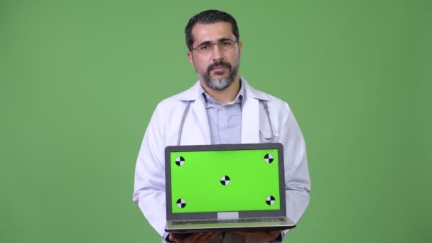 Guapo persa barbudo hombre médico mostrando portátil — Vídeos de Stock