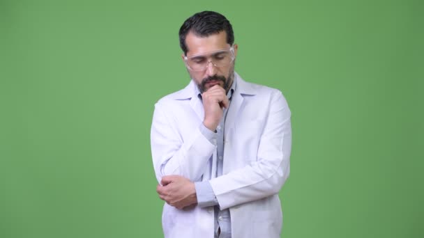 Homme barbu persan sérieux médecin portant des lunettes de protection tout en pensant — Video