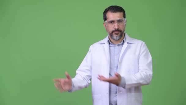 सुंदर फारसी दाढ़ी वाला आदमी डॉक्टर सुरक्षात्मक चश्मा पहनता है और कुछ दिखाता है — स्टॉक वीडियो