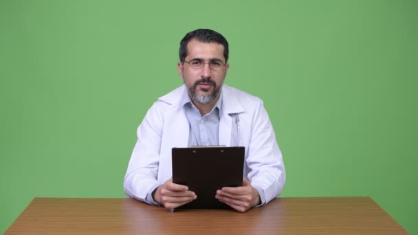 Handsome Persian bearded man doctor giving consultation while holding clipboard — Stock Video