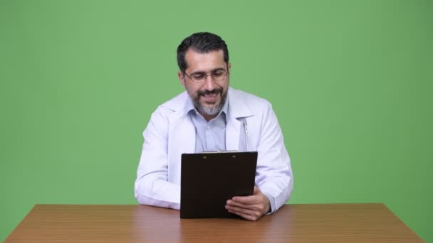 Handsome Persian bearded man doctor reading clipboard — Stock Video