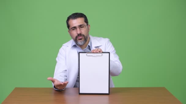 Bonito persa barbudo homem médico falando ao mostrar prancheta — Vídeo de Stock