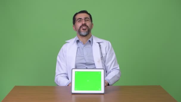 Bonito persa barbudo homem médico dando polegares para cima ao mostrar tablet digital — Vídeo de Stock