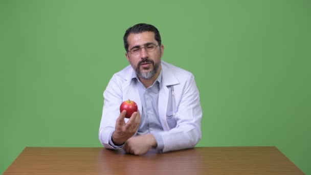 Красивый персидский бородатый врач говорит, держа яблоко — стоковое видео