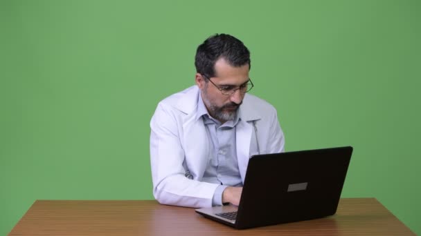 Szép perzsa szakállas férfi orvos dolgozik a laptop, és üdvözlés — Stock videók