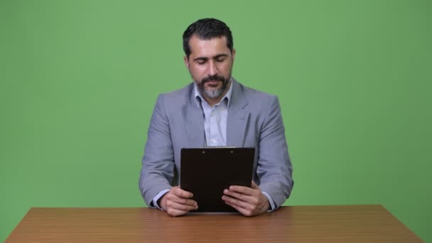 ハンサムなペルシャ髭クリップボードを押しながら思考のビジネスマン — ストック動画