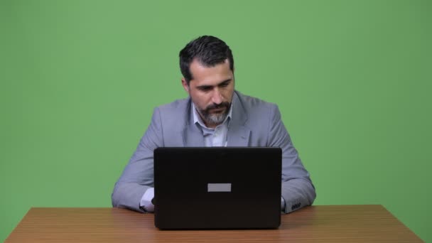 Frumos persan barbă om de afaceri gândire în timp ce utilizați laptop-ul — Videoclip de stoc