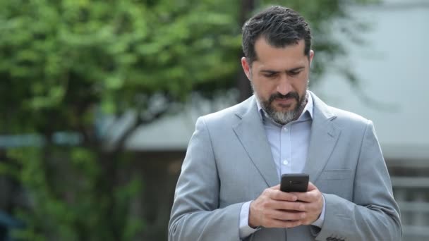 Bello persiano barbuto uomo d'affari utilizzando il telefono per le strade all'aperto — Video Stock