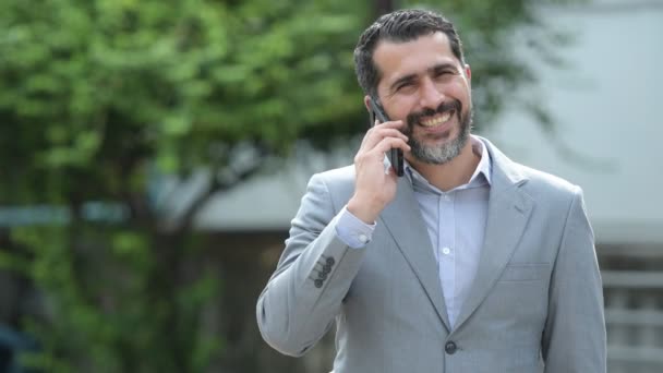 Guapo persa barbudo hombre de negocios hablando por teléfono en las calles al aire libre — Vídeo de stock