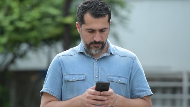 Handsome Persian bearded man using phone in the streets outdoors — Stock Video