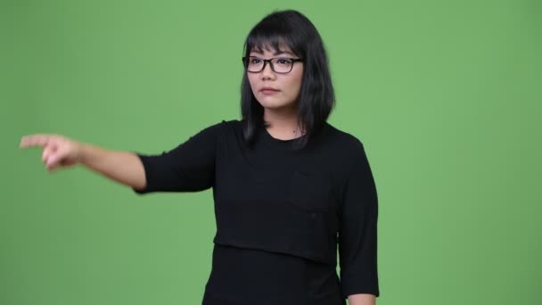 Красивая счастливая азиатская деловая женщина улыбается, указывая пальцем — стоковое видео