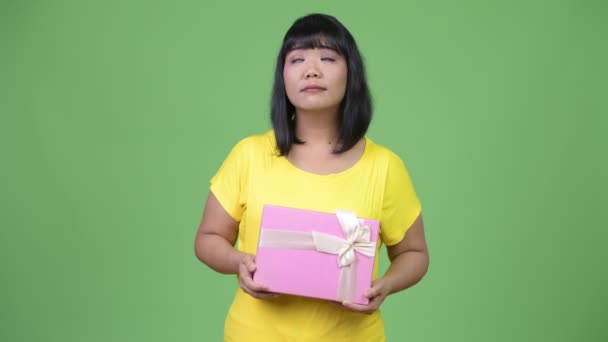 Όμορφη ευτυχισμένη γυναίκα της Ασίας σκέψης ενώ κρατάτε το κιβώτιο δώρων — Αρχείο Βίντεο