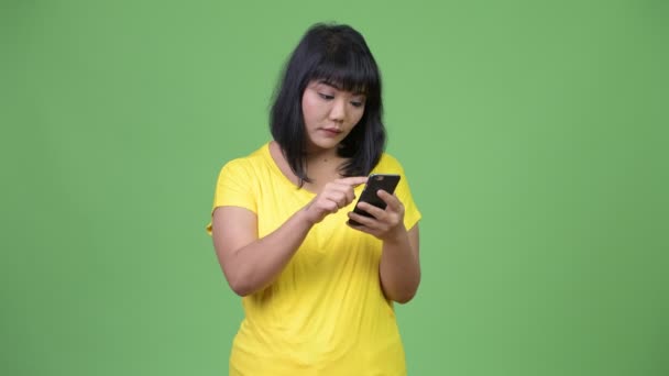 Ομορφη ευτυχισμένη γυναίκα της Ασίας χρήση τηλεφώνου, ενώ ψάχνει έκπληκτος — Αρχείο Βίντεο