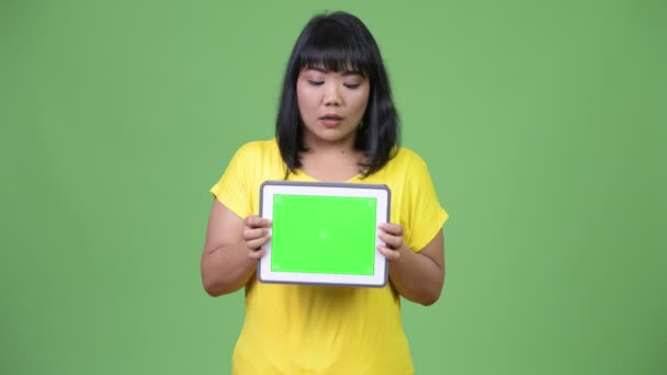 美しいアジアの女性を示すデジタル タブレットと見てショックを受けてください。 — ストック動画