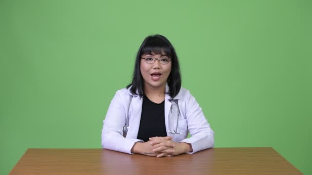 Hermosa mujer asiática médico sonriendo y saludando — Vídeos de Stock