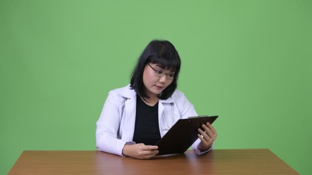 Hermosa mujer asiática médico leyendo portapapeles — Vídeo de stock