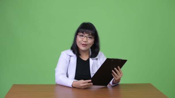 아름 다운 아시아 여자 의사 클립보드 읽기와 좋은 뉴스를 제공 — 비디오