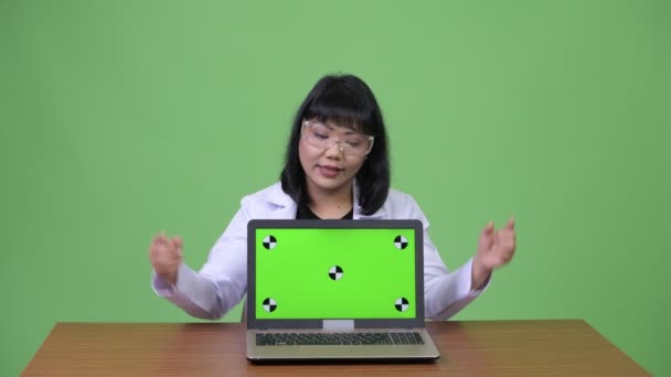 Hermosa mujer asiática médico con gafas de protección que muestra el ordenador portátil y dar pulgares hacia arriba — Vídeos de Stock
