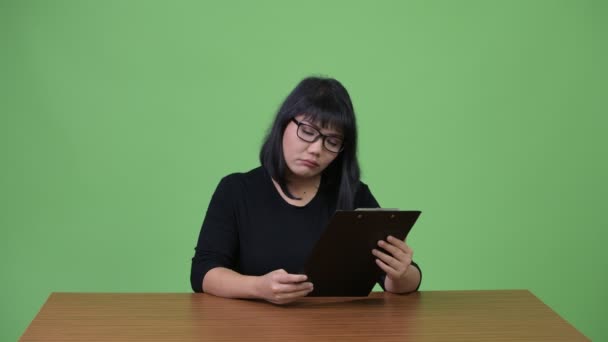 Beautiful Asian businesswoman thinking while clipboard — Stock Video