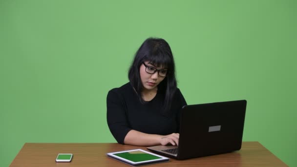 Krásné asijské podnikatelka multi-tasking a volání v práci — Stock video