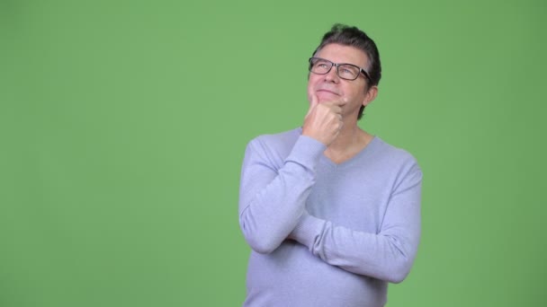 Senior knappe man denken tegen groene achtergrond — Stockvideo