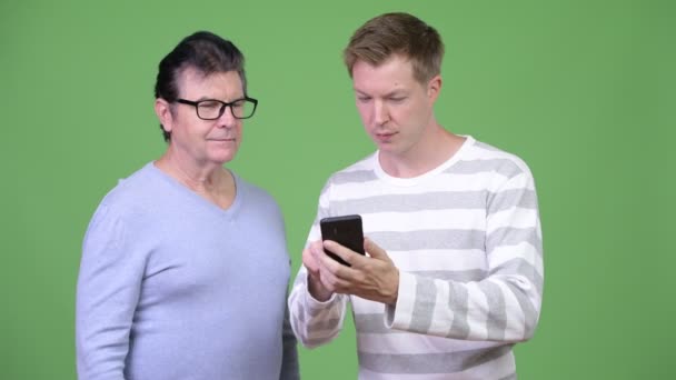 Üst düzey yakışıklı adam ve yakışıklı delikanlı telefon birlikte kullanma — Stok video