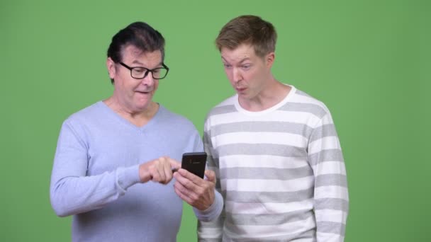 Üst düzey yakışıklı adam ve yakışıklı delikanlı telefon birlikte kullanma — Stok video