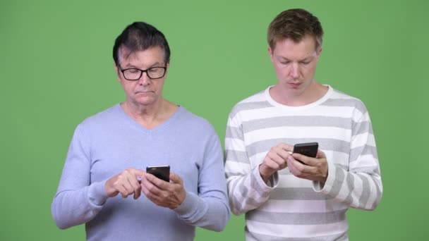 Äldre stilig man och ung stilig man använda telefonen tillsammans — Stockvideo