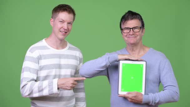 Senior gutaussehender Mann und junger gutaussehender Mann zeigen zusammen ein digitales Tablet — Stockvideo
