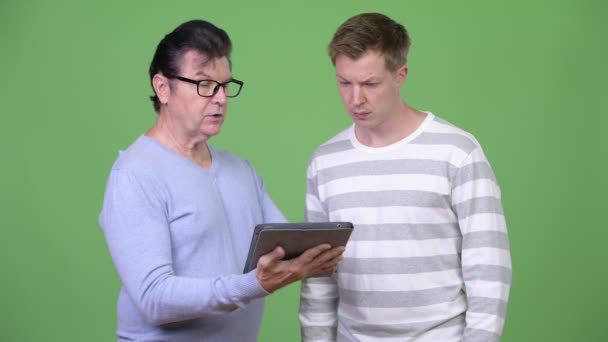 资深英俊的人和年轻英俊的人使用数字式平板电脑一起 — 图库视频影像
