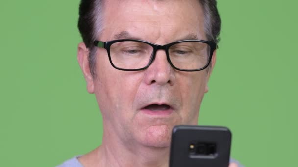 Hombre guapo mayor usando el teléfono y mirando sorprendido — Vídeos de Stock