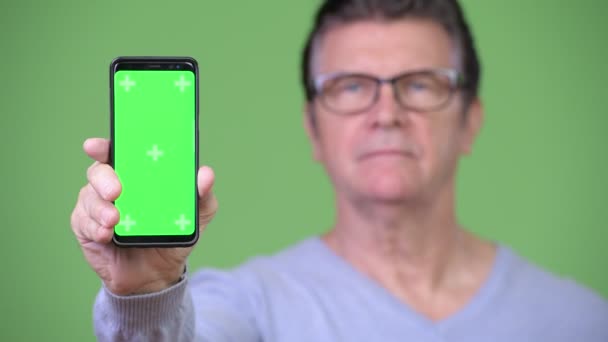 Senior schöner Mann zeigt Handy — Stockvideo