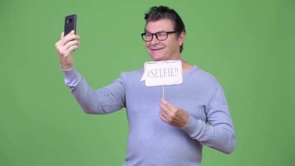 Äldre stilig man tar selfie med papper skylt — Stockvideo