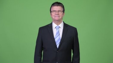 Üst düzey yakışıklı işadamı yeşil bir arka plana dayanır