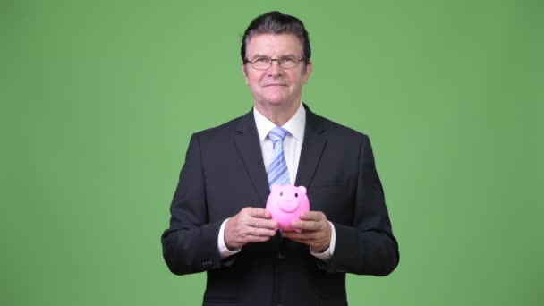 Hombre de negocios guapo señalando a Piggy Bank — Vídeos de Stock