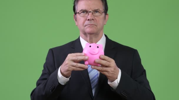 Senior knappe zakenman piggy bank holding en geven duimen omhoog — Stockvideo