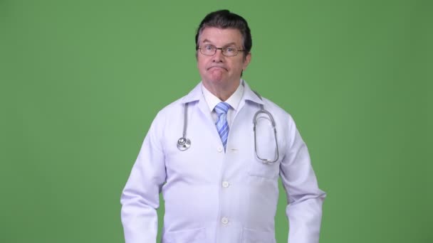 Старший привлекательный врач говорит, пожимая плечами — стоковое видео
