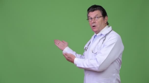 Senior guapo hombre doctor mostrando algo — Vídeo de stock