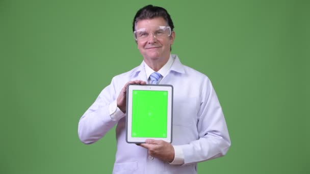 Senior schöner Mann Arzt mit Schutzbrille zeigt digitales Tablet — Stockvideo