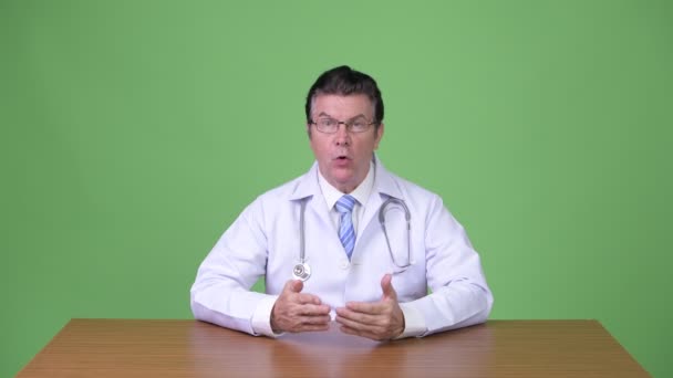 緑の背景にクロマキーに対して年配のハンサムな男性医師のスタジオ撮影 — ストック動画