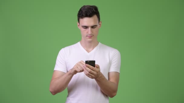 Молодой красивый мужчина думает, пользуясь телефоном — стоковое видео
