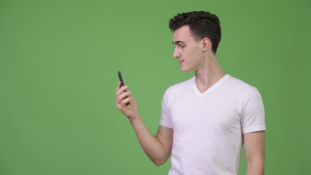 Joven hombre guapo vídeo llamando y mostrando el teléfono — Vídeos de Stock