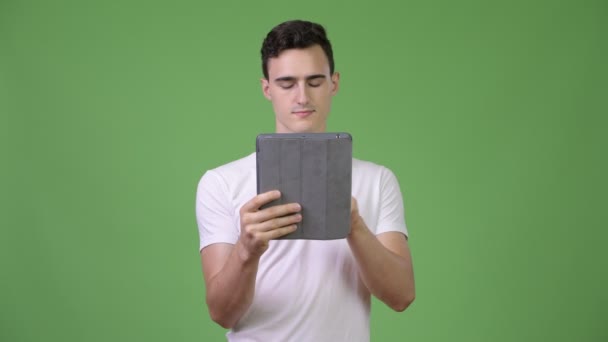 Jovem homem bonito pensando ao usar tablet digital — Vídeo de Stock