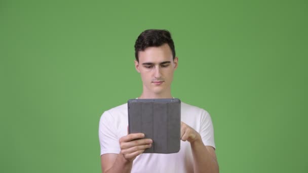 Jeune homme beau utilisant une tablette numérique et obtenir de bonnes nouvelles — Video