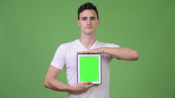 Joven hombre guapo mostrando tableta digital — Vídeos de Stock