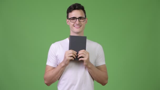 Young handsome nerd man holding book — Stock Video