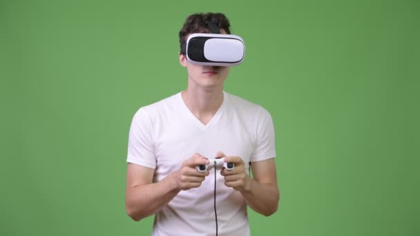 Jovem homem bonito jogando jogos enquanto usa fone de ouvido realidade virtual — Vídeo de Stock