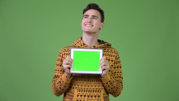 Jovem homem bonito pensando ao mostrar tablet digital — Vídeo de Stock