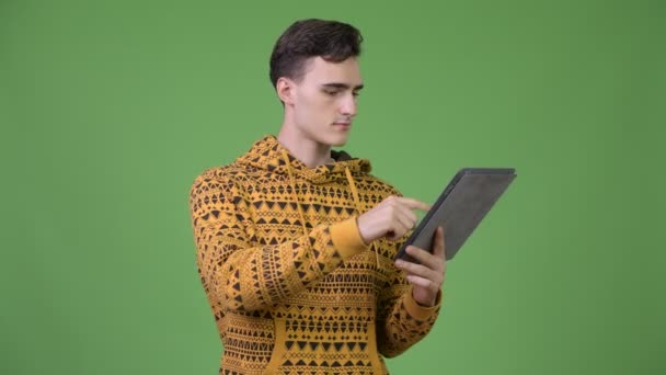 Joven hombre guapo usando tableta digital y recibiendo buenas noticias — Vídeos de Stock