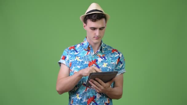 Joven guapo turista hombre usando tableta digital y recibiendo buenas noticias — Vídeo de stock